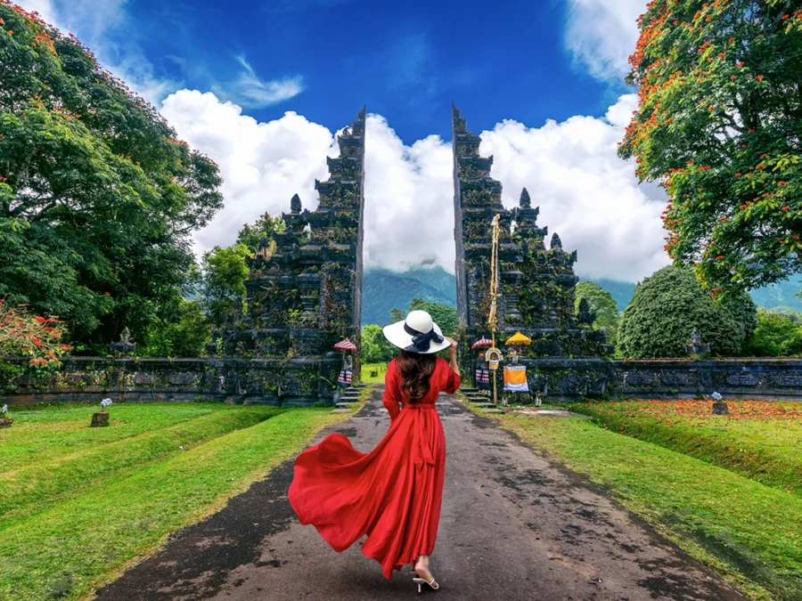 Woman walking at big entrance gate, bali in indonesia.